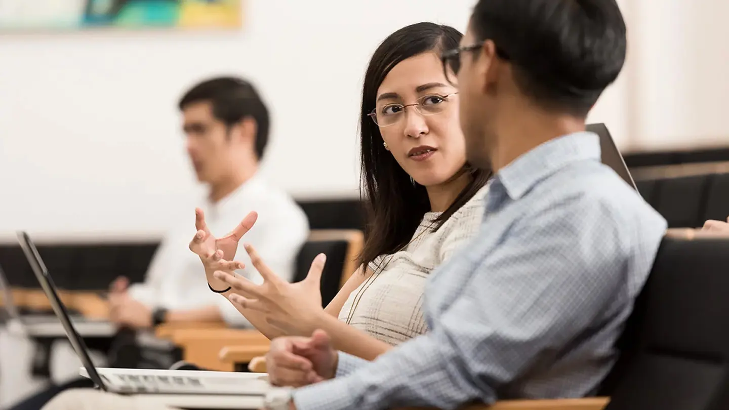 Business professionals discussing ideas during a meeting in a training or seminar setting.