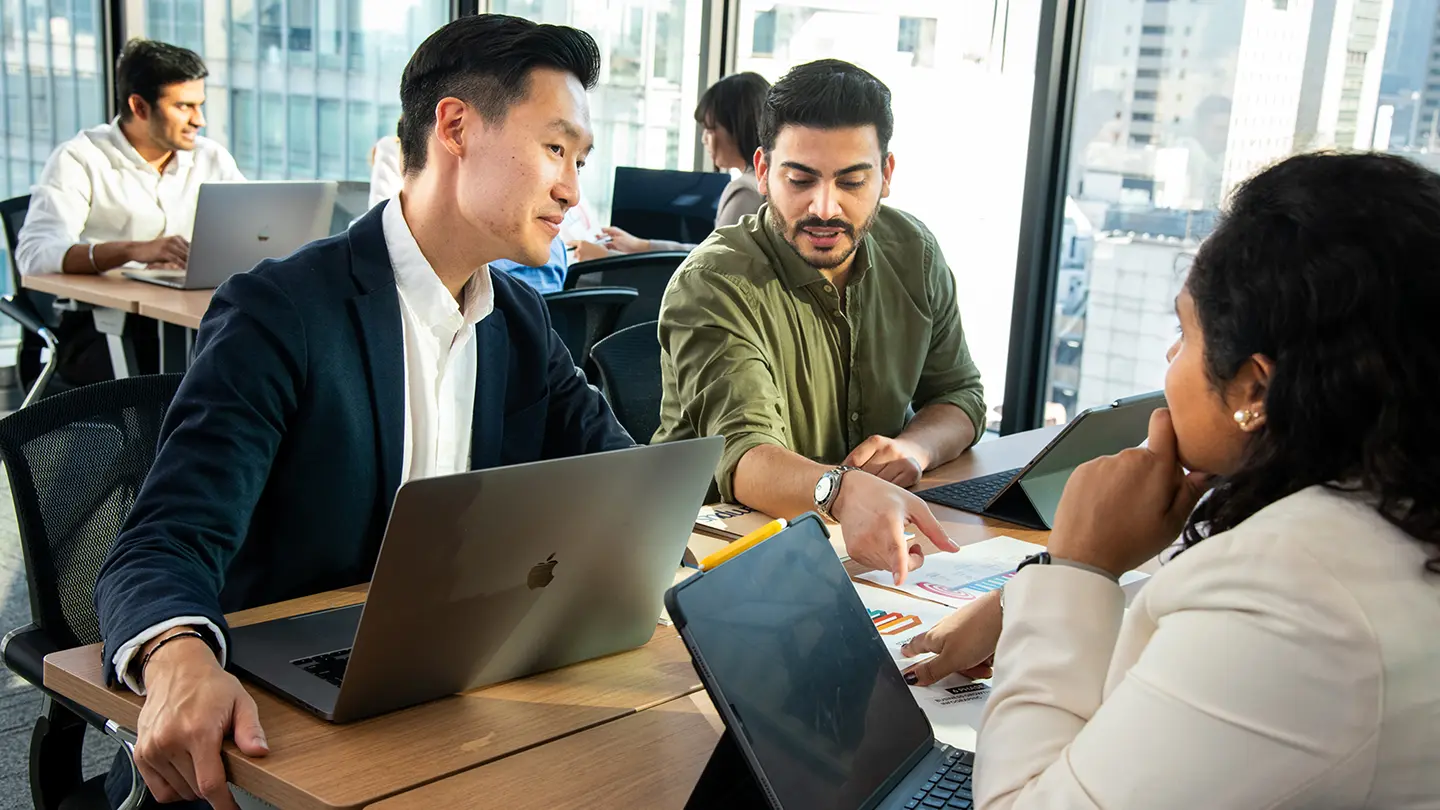 Business team collaborating around laptops and documents in a modern office.
