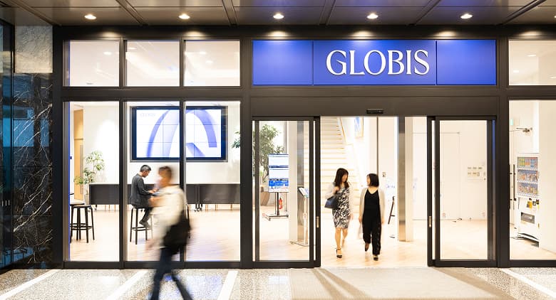 Entrance to the GLOBIS office with people walking in and out, including visible interior seating and a digital display