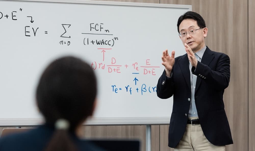 An instructor explaining formulas to a learner using a whiteboard in a classroom setting