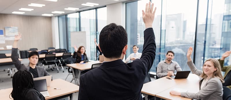 Business professionals actively participating with raised hands during a corporate training session