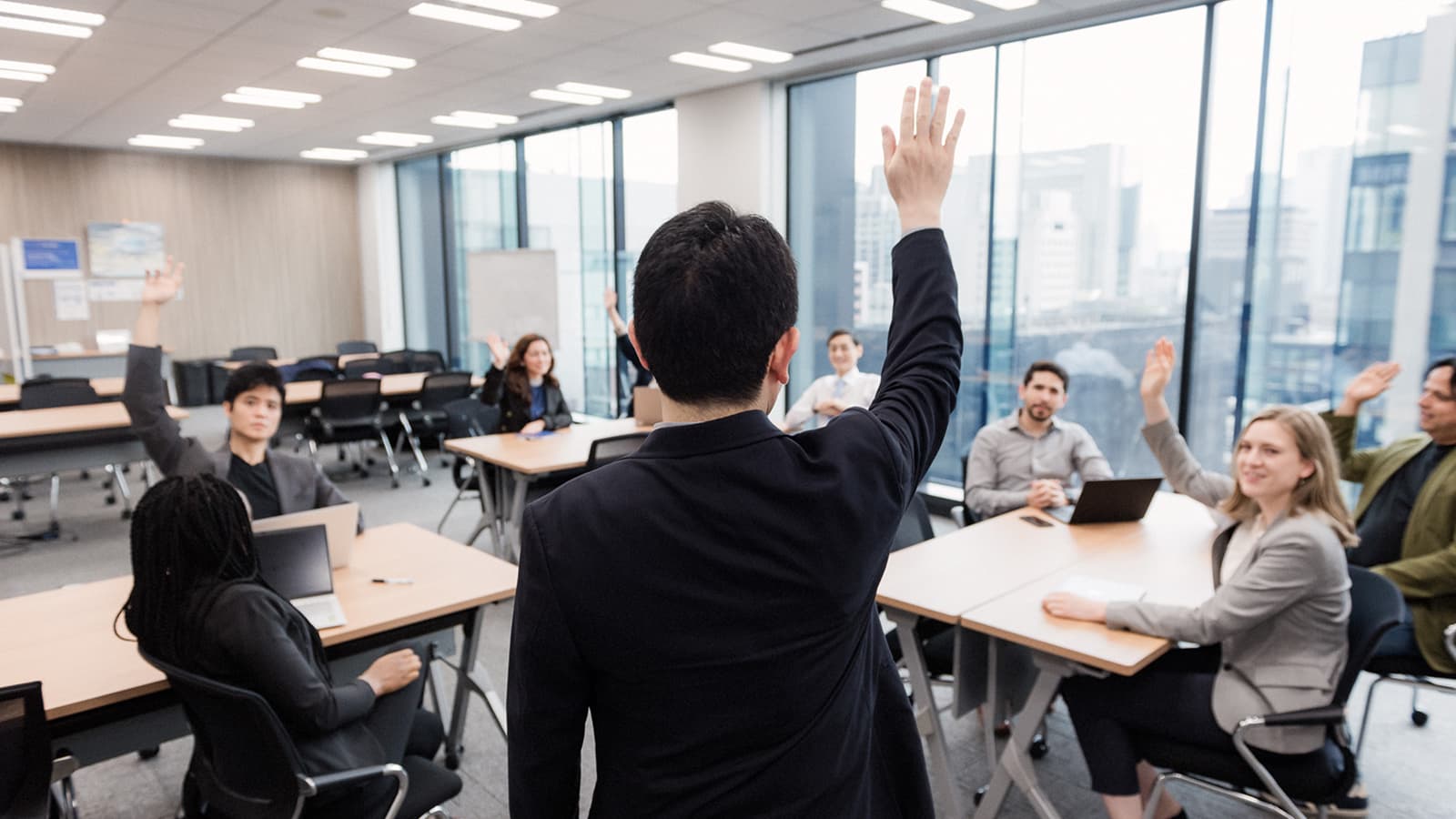 Business professionals actively participating with raised hands during a corporate training session
