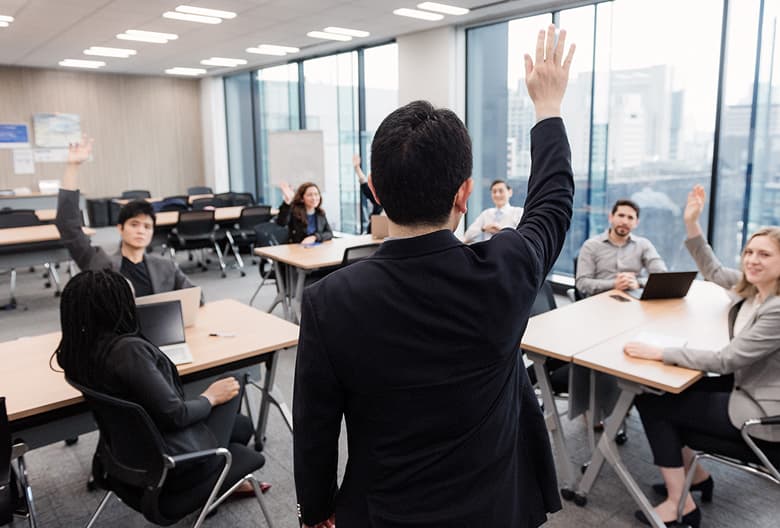 Business professionals actively participating with raised hands during a corporate training session