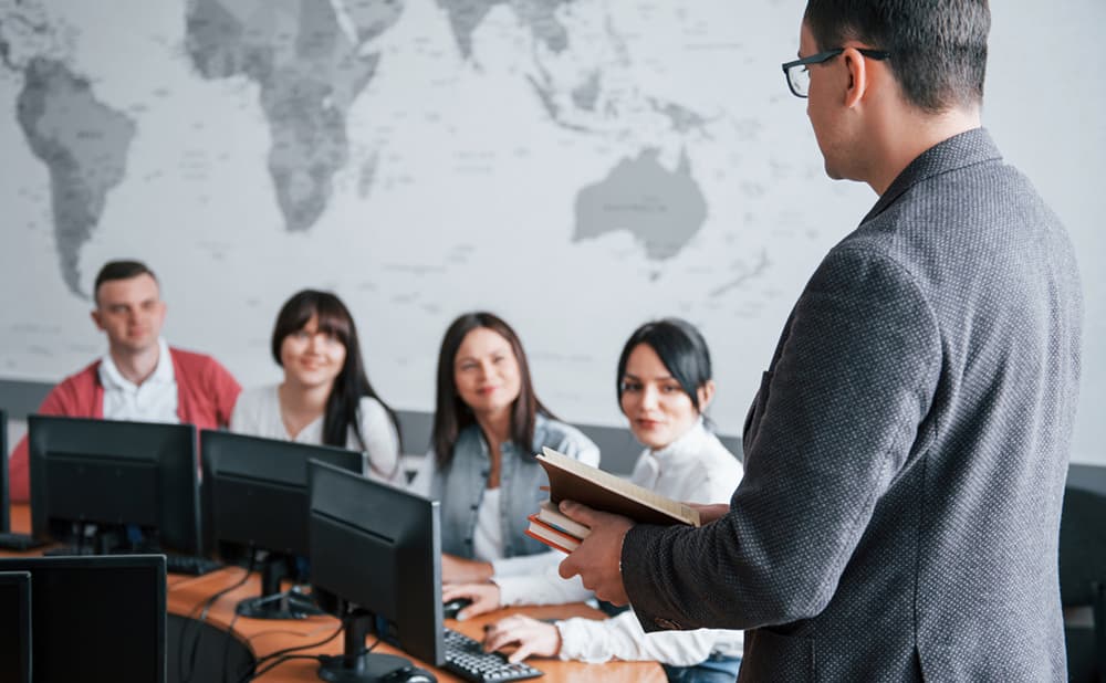 Business professionals attending a lecture while working on desktop computers in a meeting room