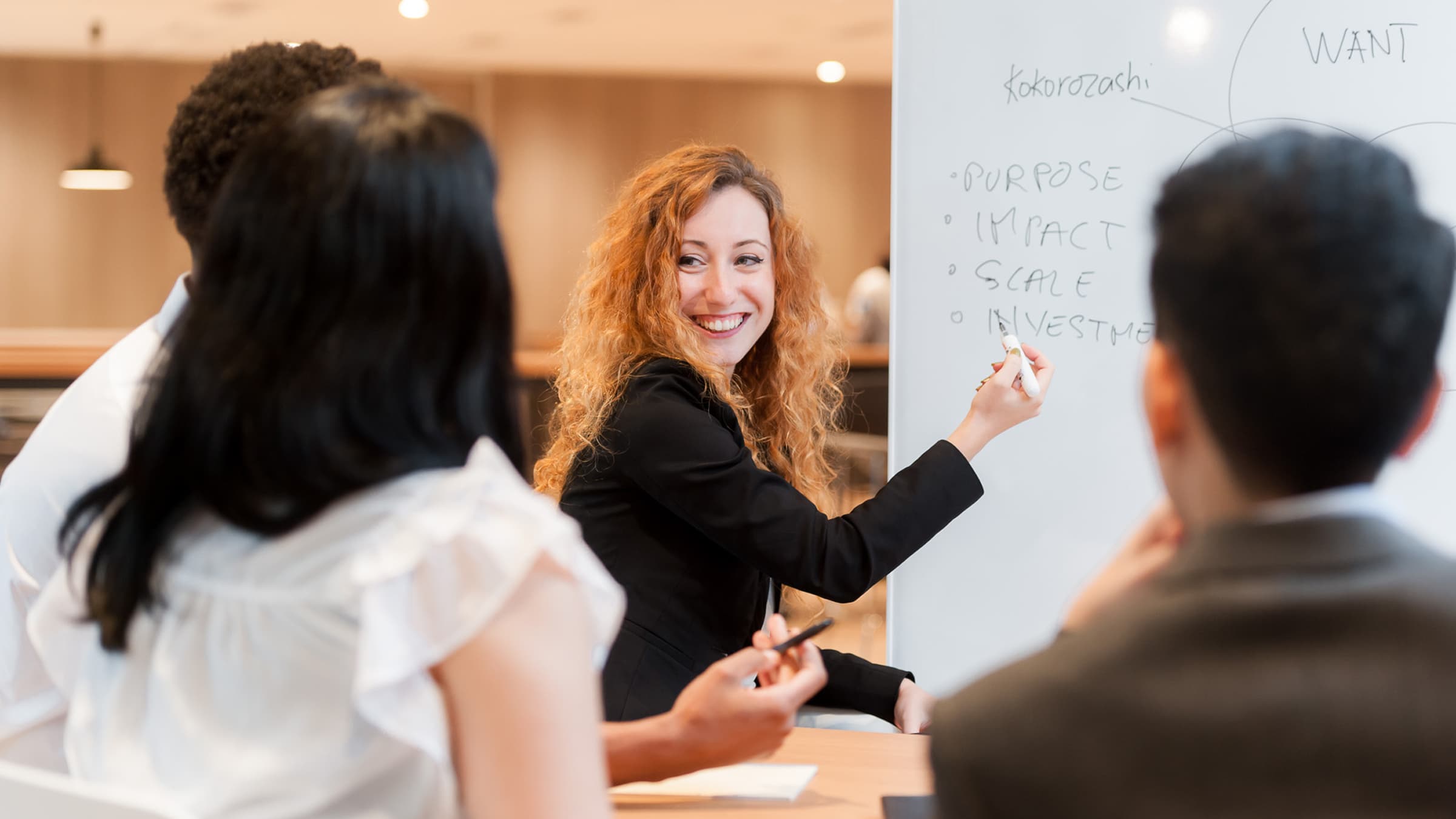 A female instructor speaking confidently while two professionals listen attentively in a training session
