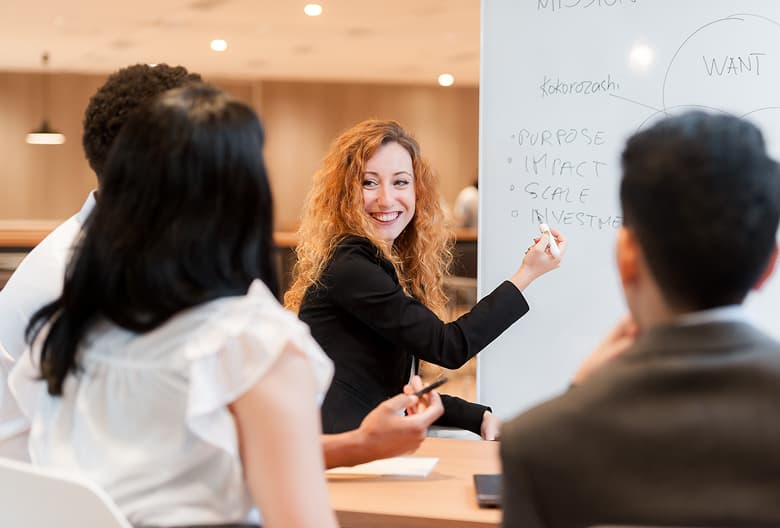 A female instructor speaking confidently while two professionals listen attentively in a training session