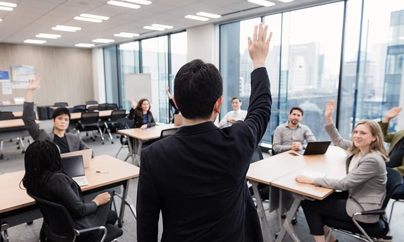 Business professionals actively participating with raised hands during a corporate training session