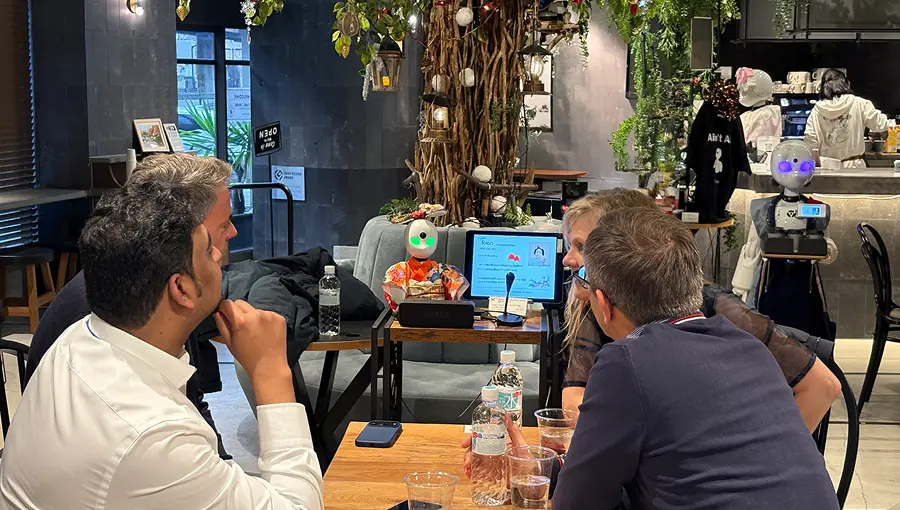 People interacting with service robots at a Avatar Robot Cafe demonstrating AI and robotics applications.