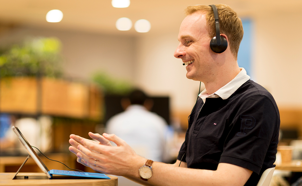 A smiling man wearing a headset while participating in a corporate training session